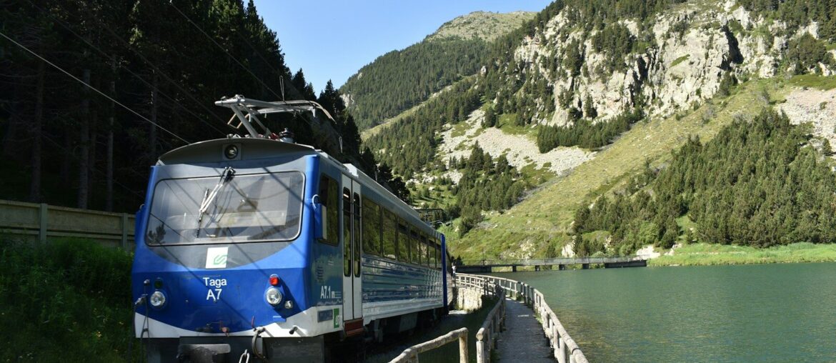 blue and white train on rail tracks near body of water during daytime