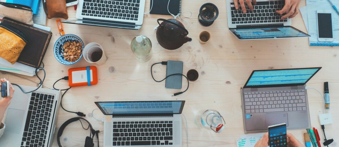 people sitting down near table with assorted laptop computers